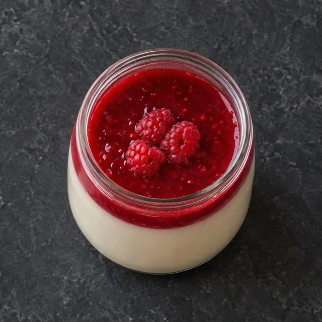 Panna cotta en pot de verre, coulis et framboises.
