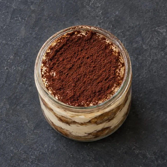 Tiramisu en pot de verre, saupoudré de cacao.